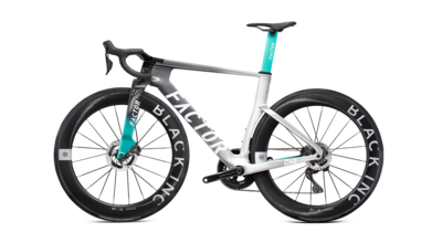 Road bike side view showing black tires, teal fork, and light silver frame