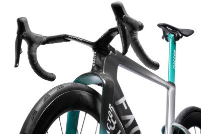 Road bike close-up showing aero handlebars, front wheel, and teal fork accents