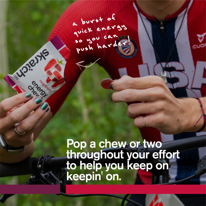Raspberry energy chew wrapper held outdoors near a cyclist, sport fuel