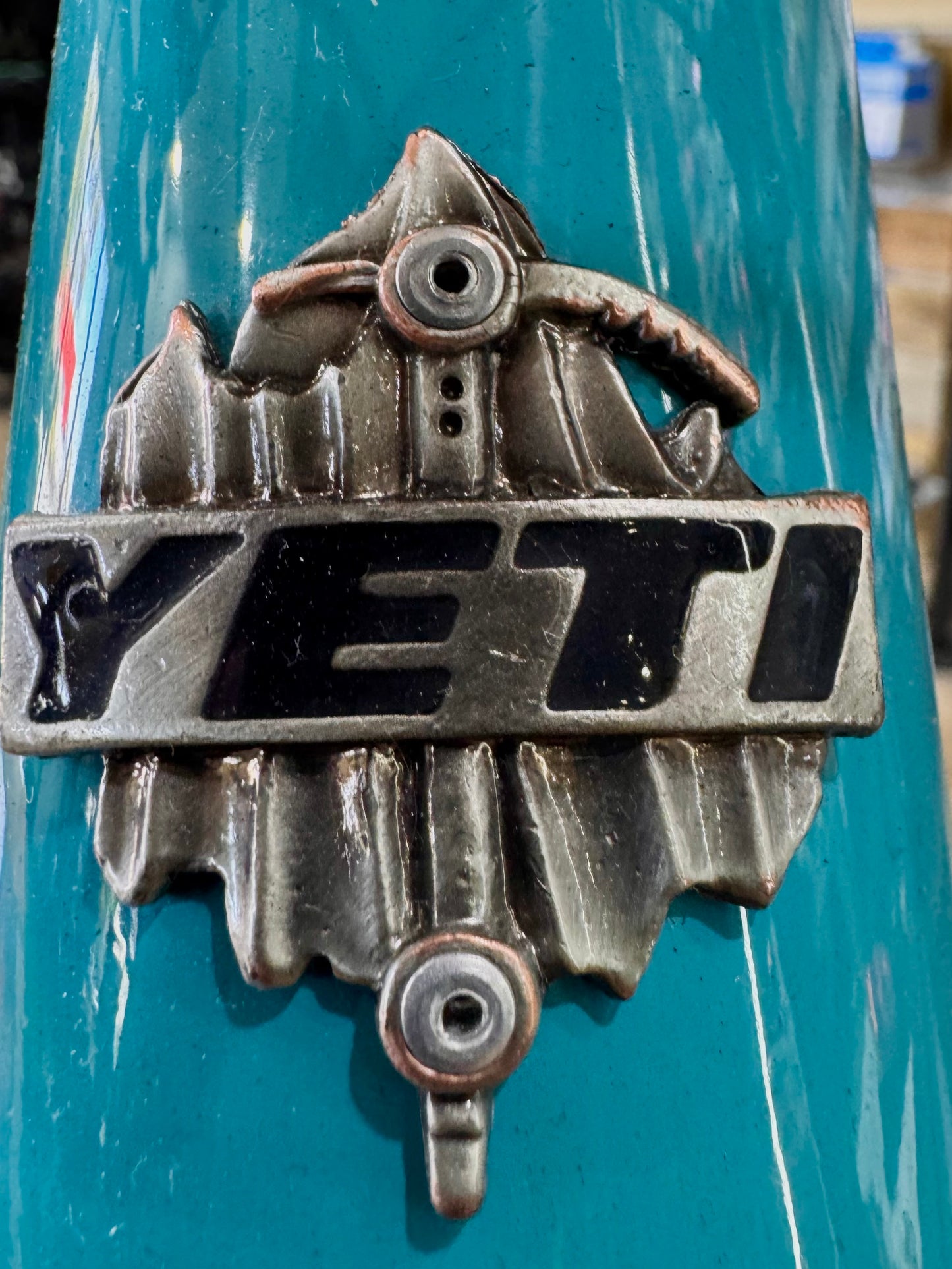 Close-up of front fork crown and headset area on turquoise electric mountain bike