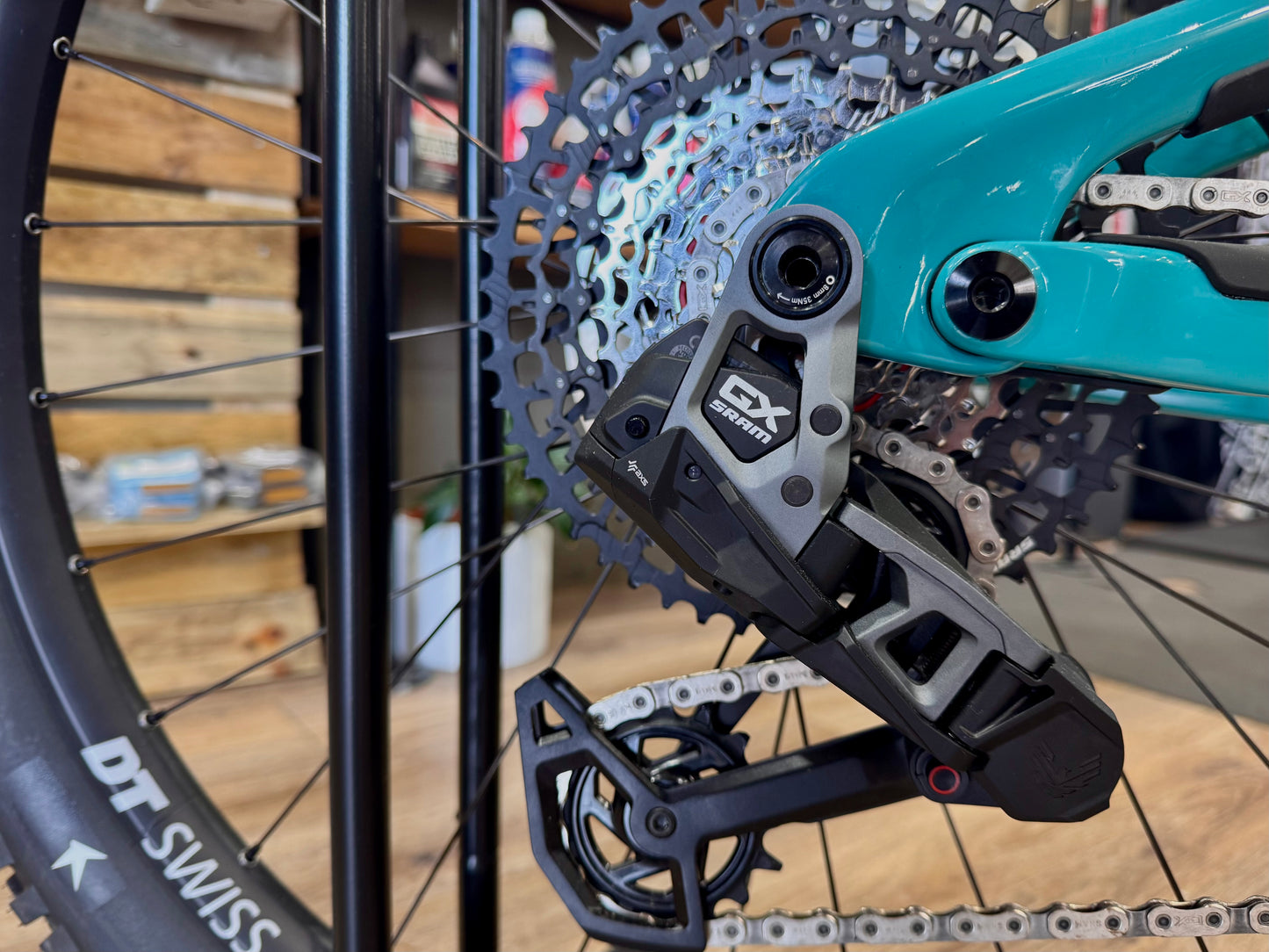 Rear wheel and cassette area with disc rotor and e-bike motor on turquoise frame