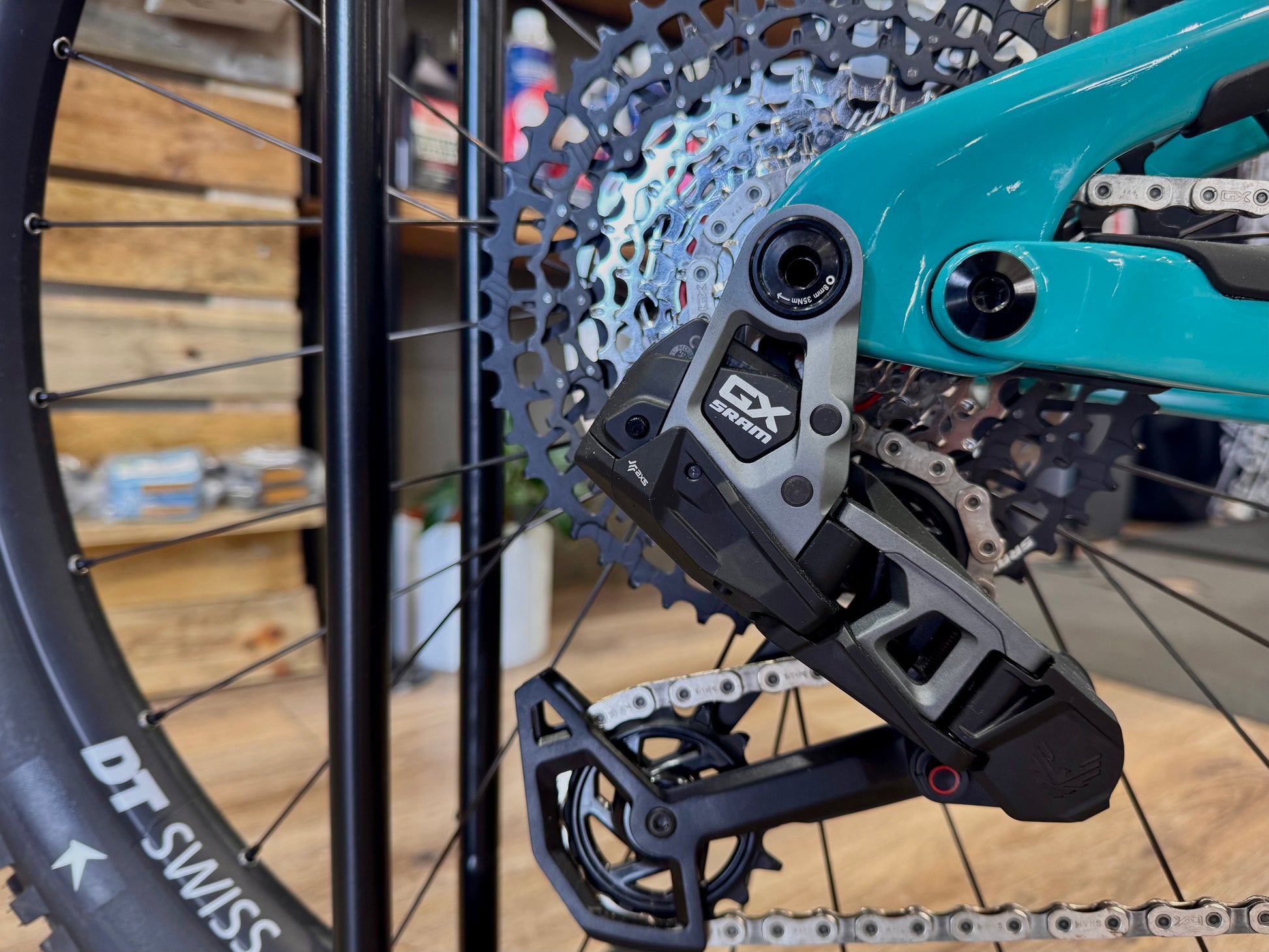 Rear wheel and cassette area with disc rotor and e-bike motor on turquoise frame